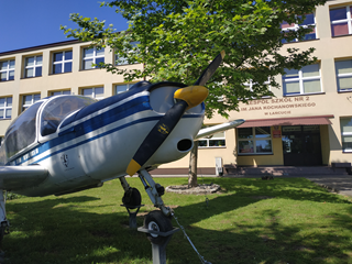 Samolot przed budynkiem szkoły