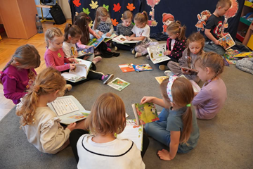 Miesiąc Bibliotek Szkolnych - dzieci czytające na dywanie.